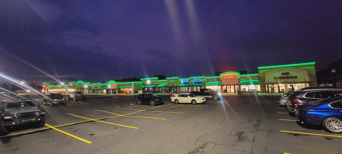 Retail strip center with green permanent roofline lighting at dusk
