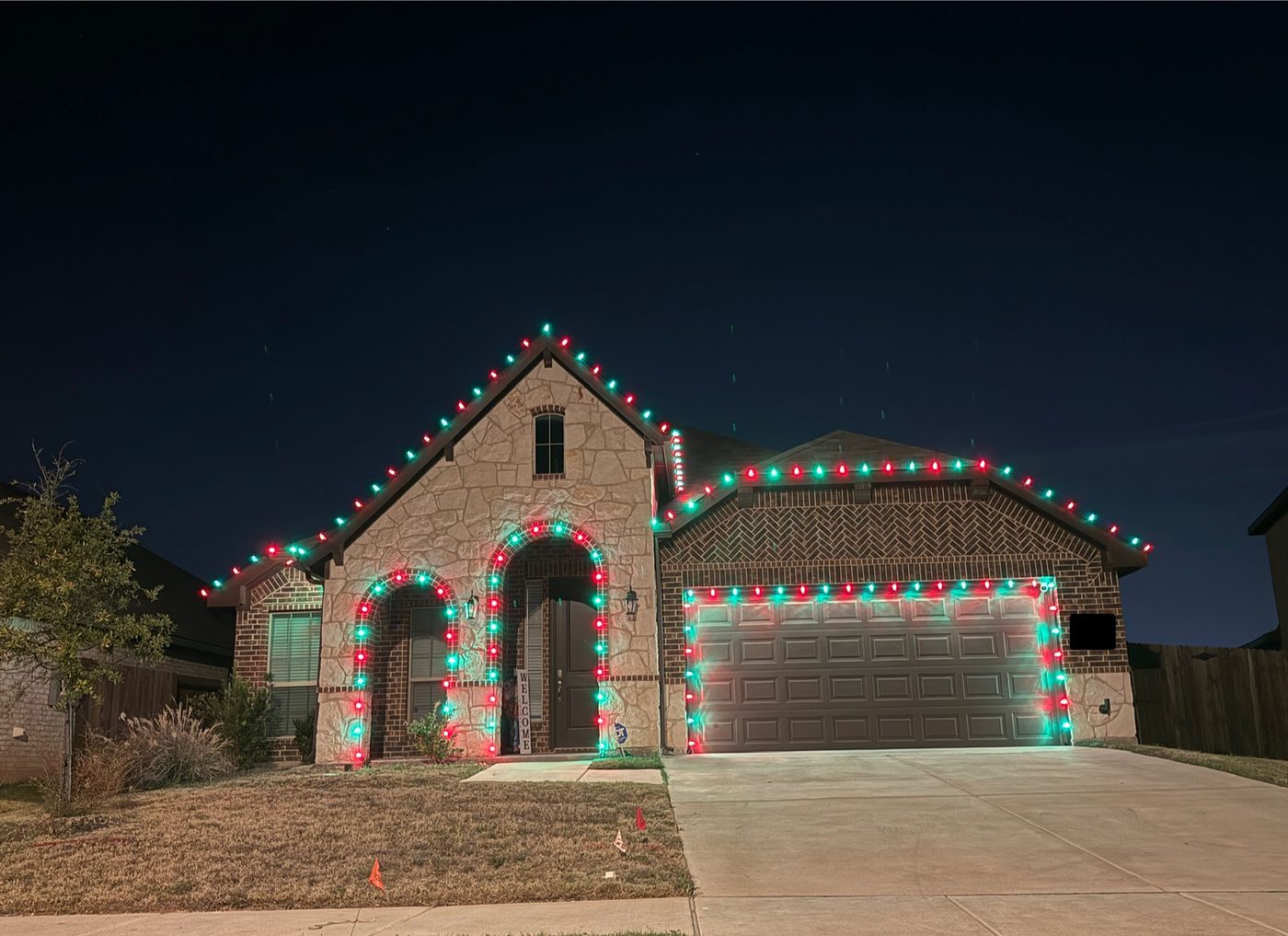 Home decorated in red and green permanent lighting for the holidays