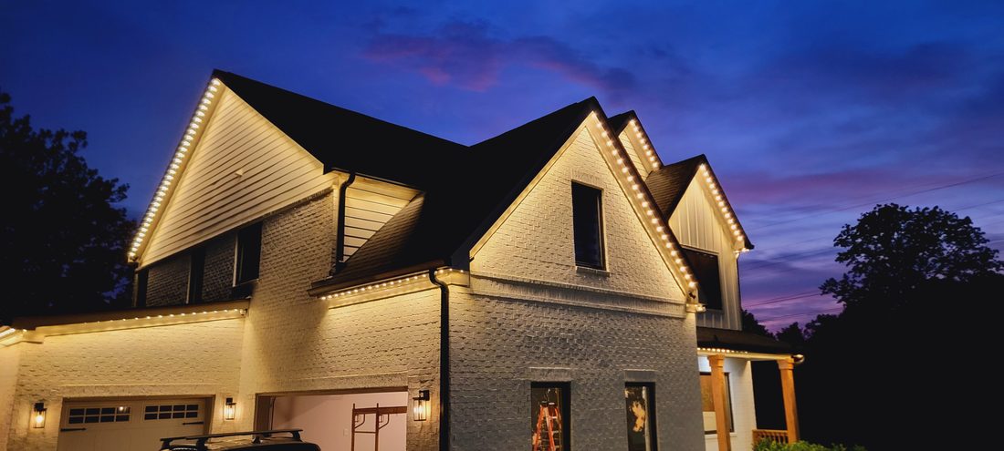 Home with warm white permanent lighting along multiple roof gables at dusk