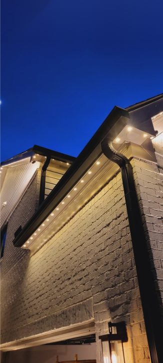 Close-up of warm white permanent lighting along a brick roofline