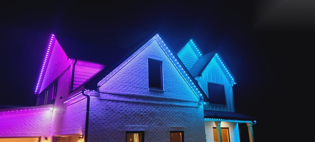 Home roofline lit in purple, blue, and cyan permanent lighting