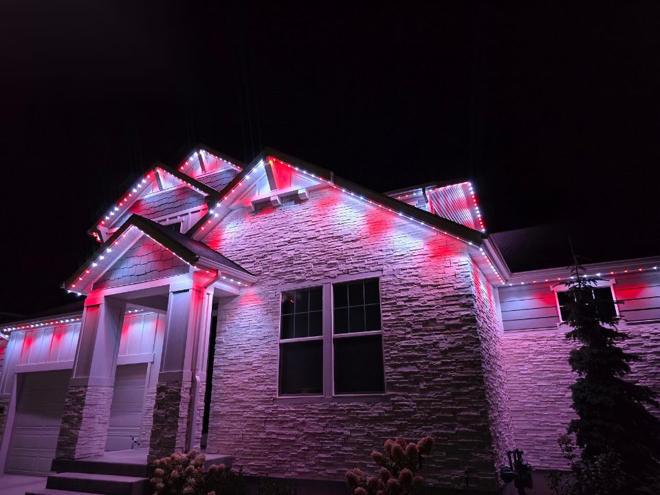 Stone home with red permanent lighting along the roofline