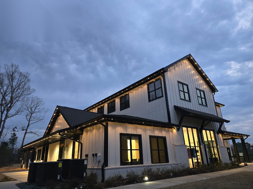 Large home with warm white permanent lighting under a cloudy dusk sky
