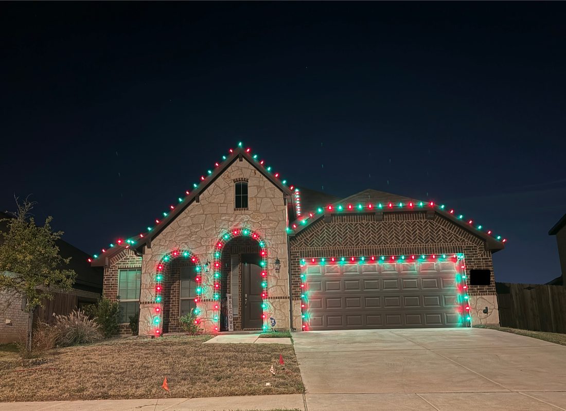 Home decorated in red and green holiday lighting along the roofline