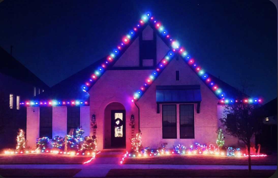 Home roofline decorated in blue, red, and green holiday lighting