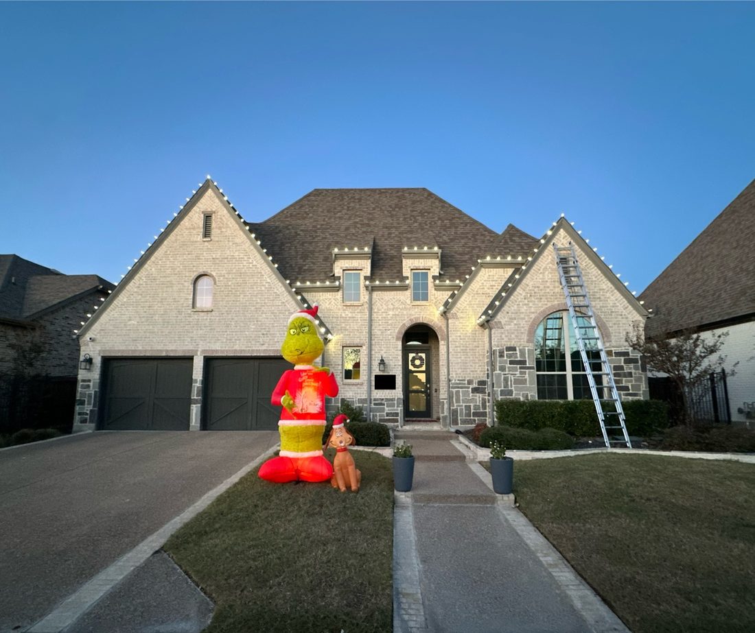 Home with holiday lighting and lawn inflatables at dusk